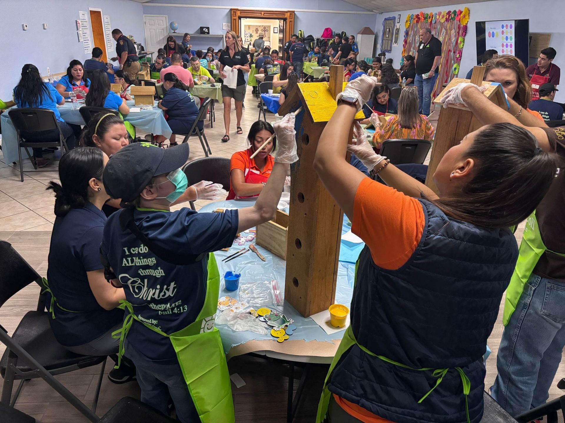 A group of people are working on a birdhouse in a room.