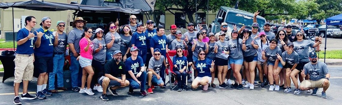 A large group of people are posing for a picture in a parking lot.