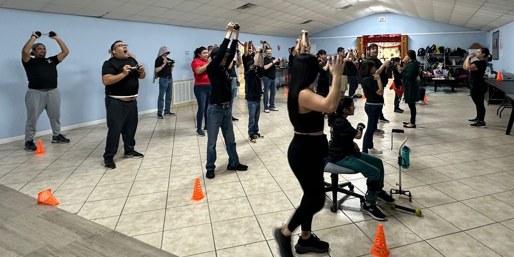 A group of people are dancing in a room with cones on the floor