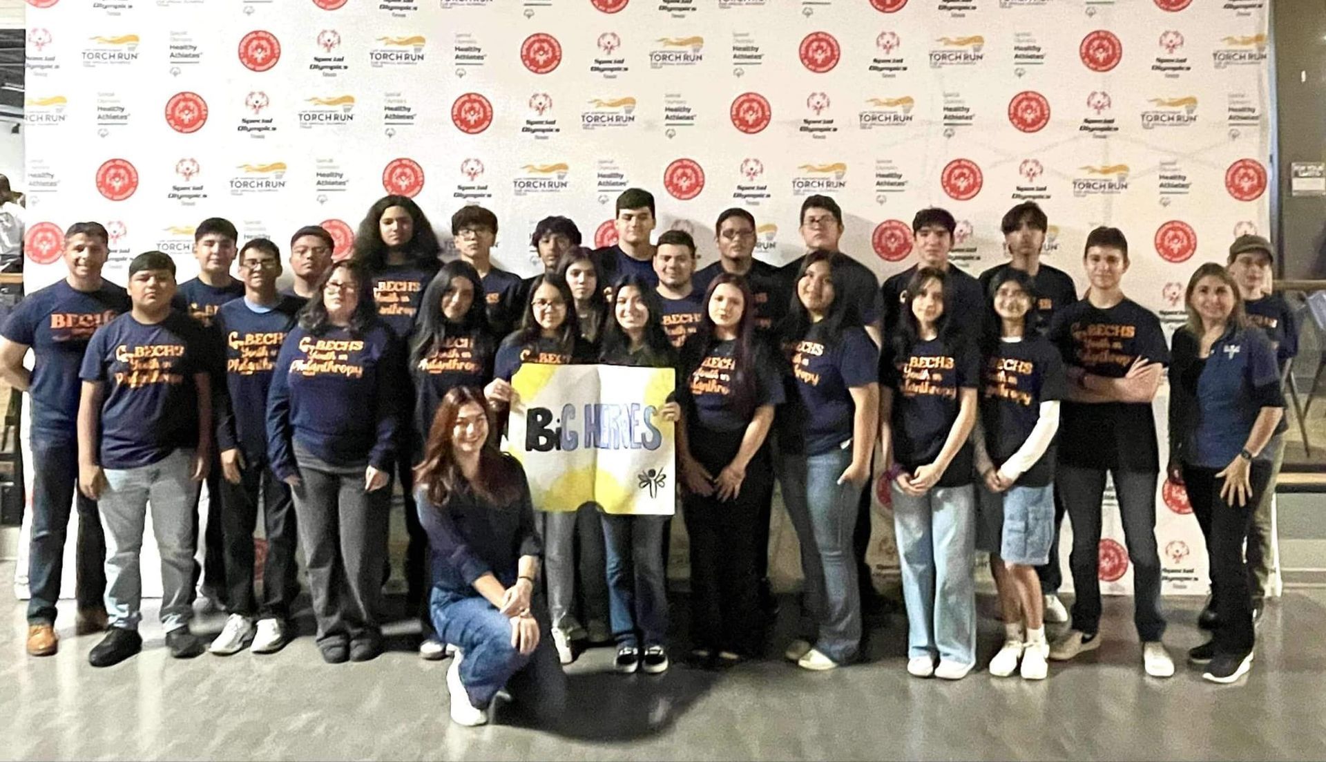 A group of people are posing for a picture in front of a wall.