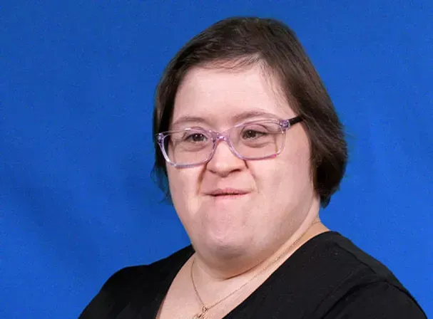 A woman with down syndrome is wearing glasses and a black shirt.