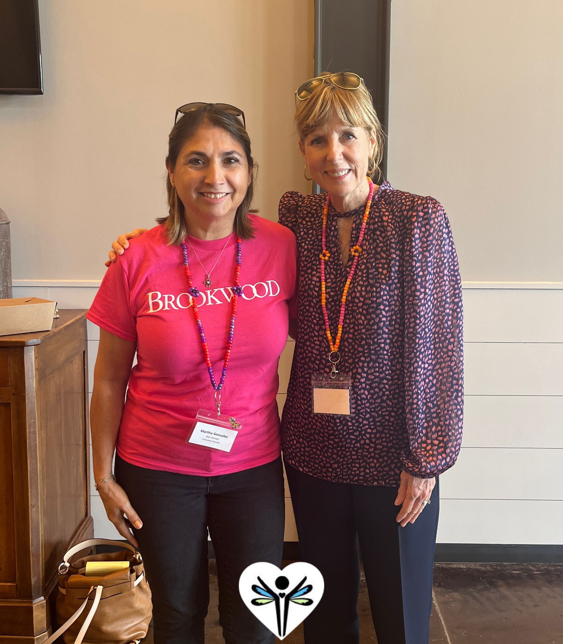Two women posing for a picture with one wearing a pink shirt