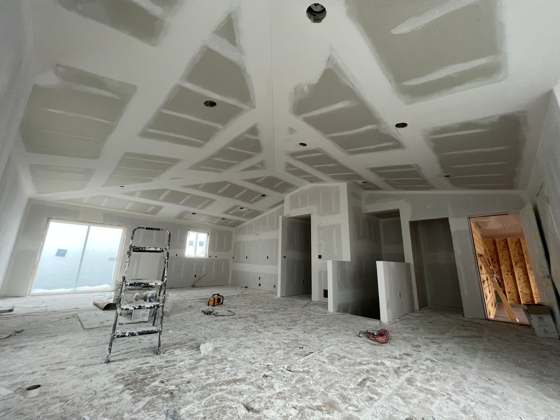 A man wearing a hard hat and safety vest is plastering a wall.