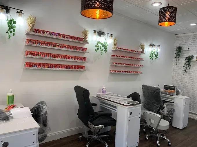 Interior of a nail salon with nail polish shelves, manicure stations, and black chairs.
