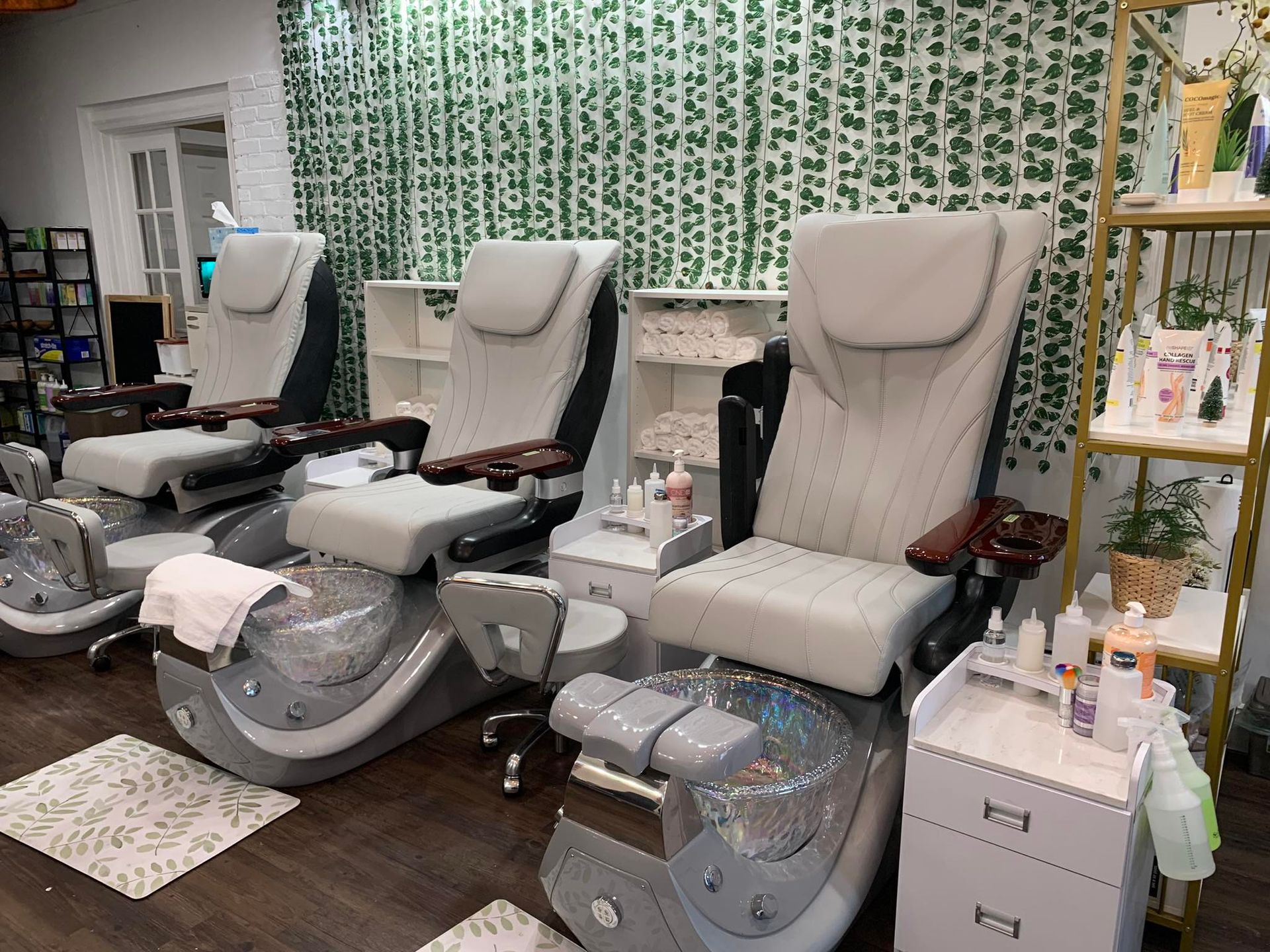 Pedicure spa interior with three reclining chairs and a shelf of products.