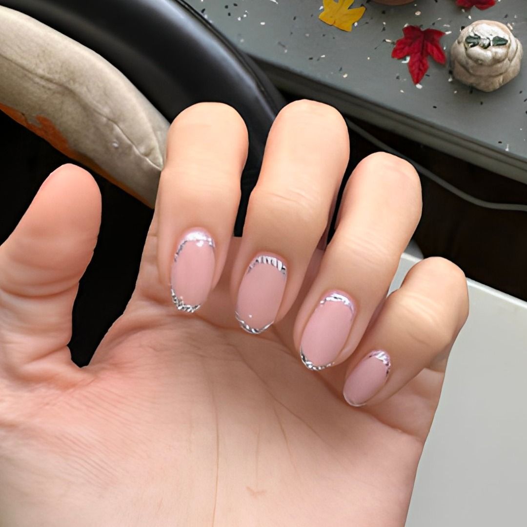 Hand with pink oval nails, silver tips.