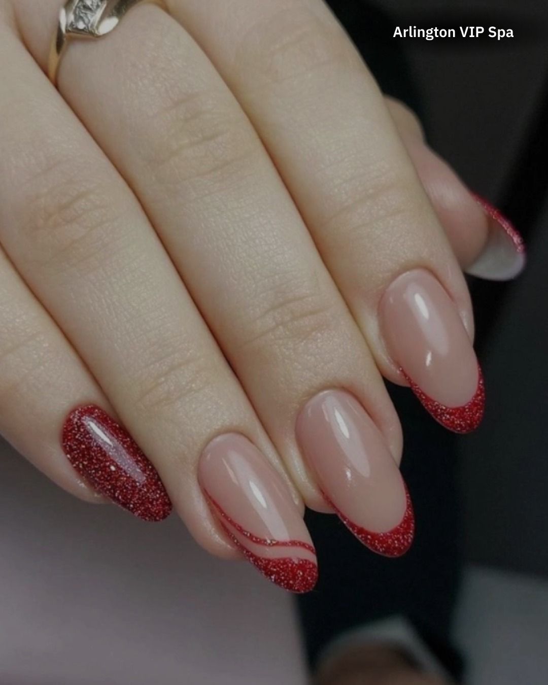 Woman's hand with red glitter accent nail and French tip nails with red glitter trim.