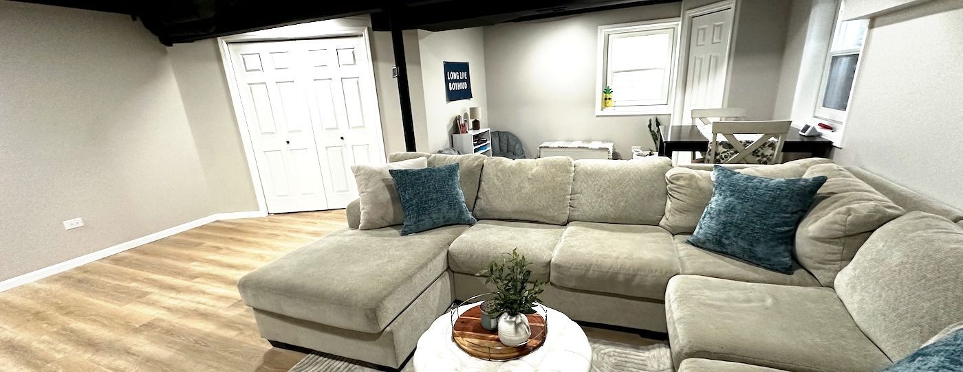 Living room with a large beige sectional sofa, teal pillows, and a round coffee table.