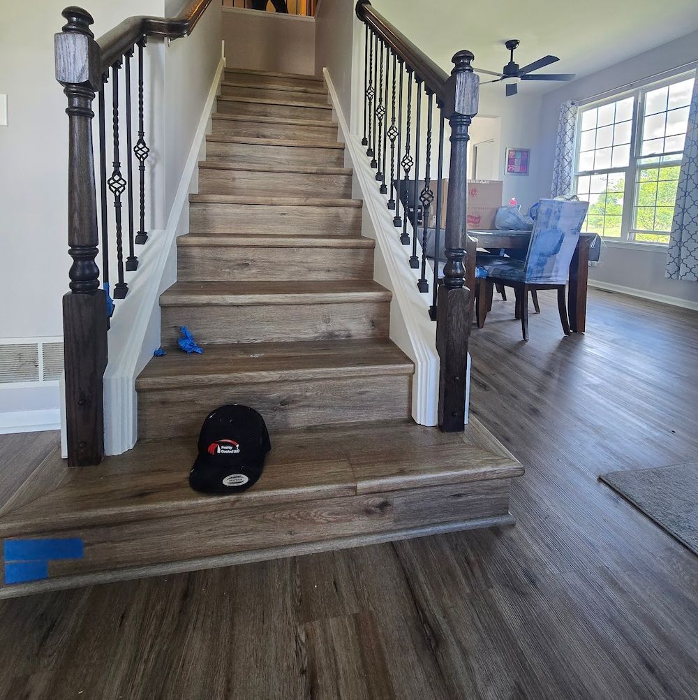 Staircase with wood-look steps and a black baseball cap on the landing; dining area visible in the background.
