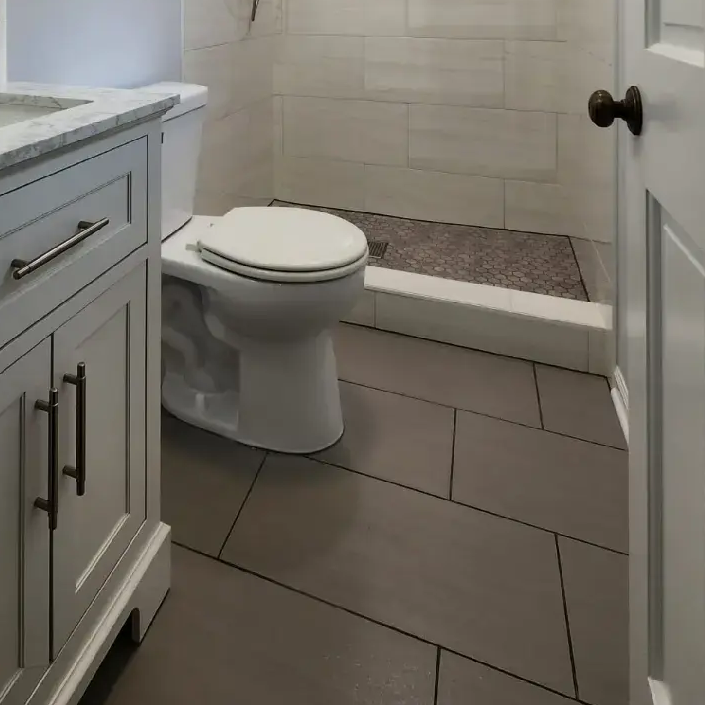 Bathroom with gray tile floor, white toilet, vanity, and shower.