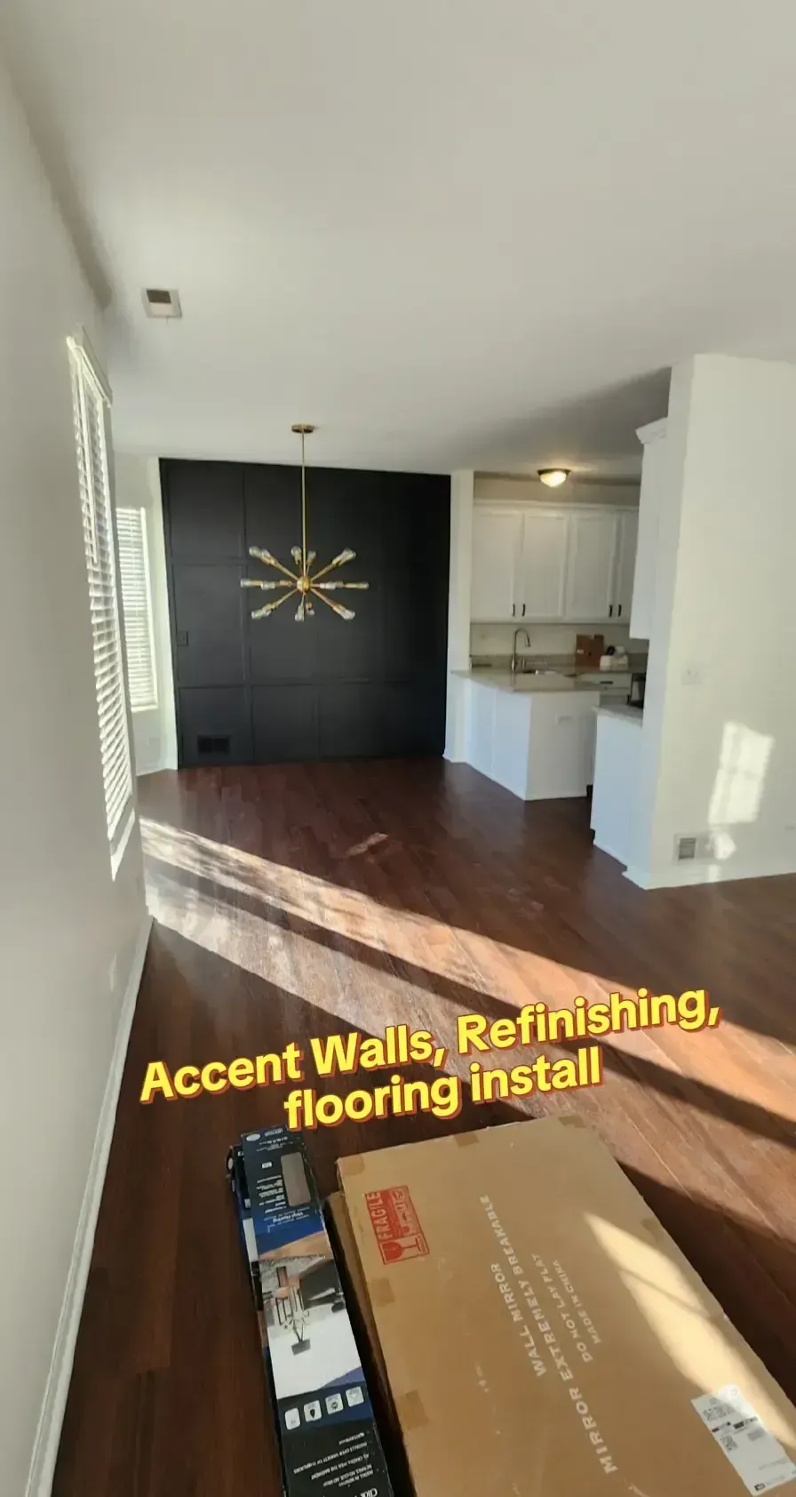 Interior with dark accent wall, hardwood floors, and boxes of flooring; refinishing project.