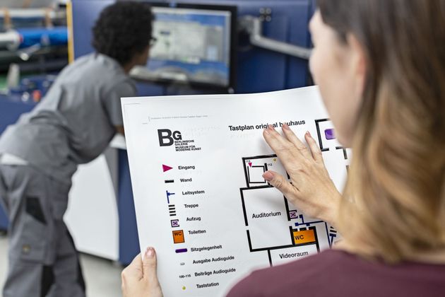Reparto di stampa produzione con macchina digitale industriale e controllo qualità da parte di un operatore.