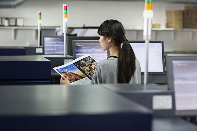 Postazione aziendale con stampante multifunzione, laptop con dashboard documentale e ambiente ufficio moderno e ordinato.