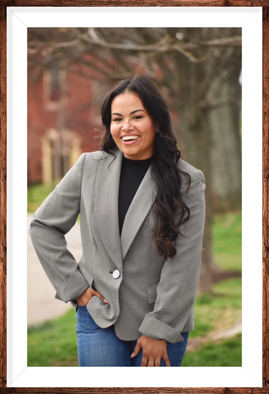 A woman is sitting at a desk with a laptop and a vase of flowers.