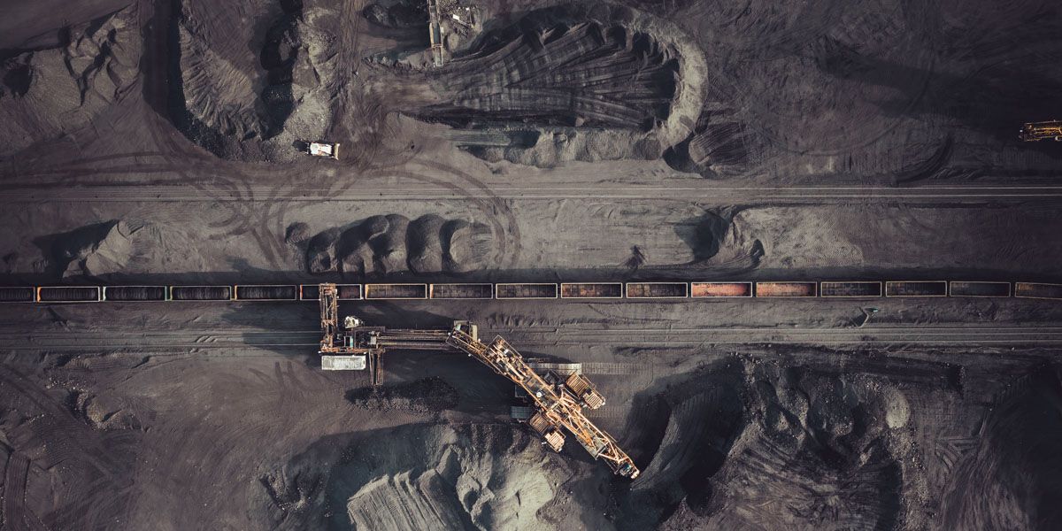 An aerial view of a coal mine with a train going through it.