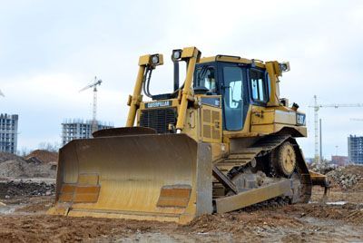 A bulldozer is sitting on top of a dirt field at a construction site.