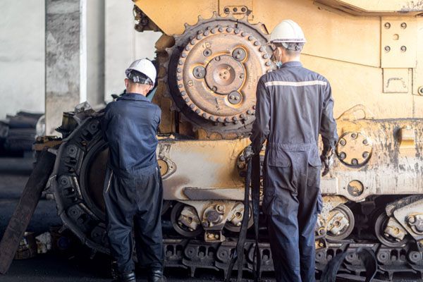 Two men are working on a large machine in a factory.