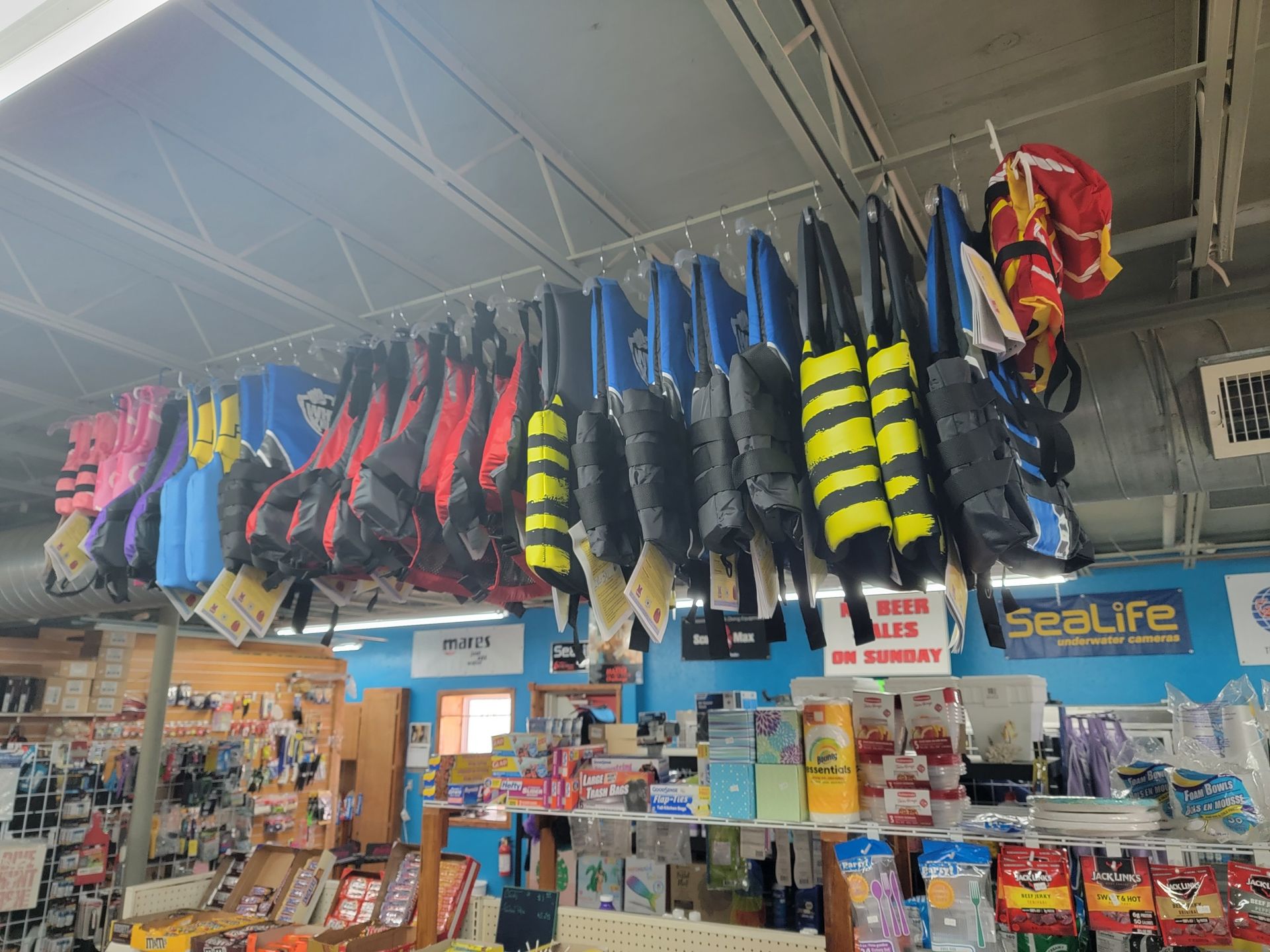 A bunch of life jackets are hanging from the ceiling of a store