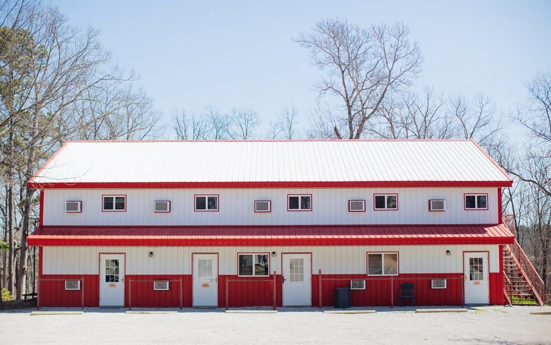 A red and white motel with a red roof and stairs near Beaver Lake.