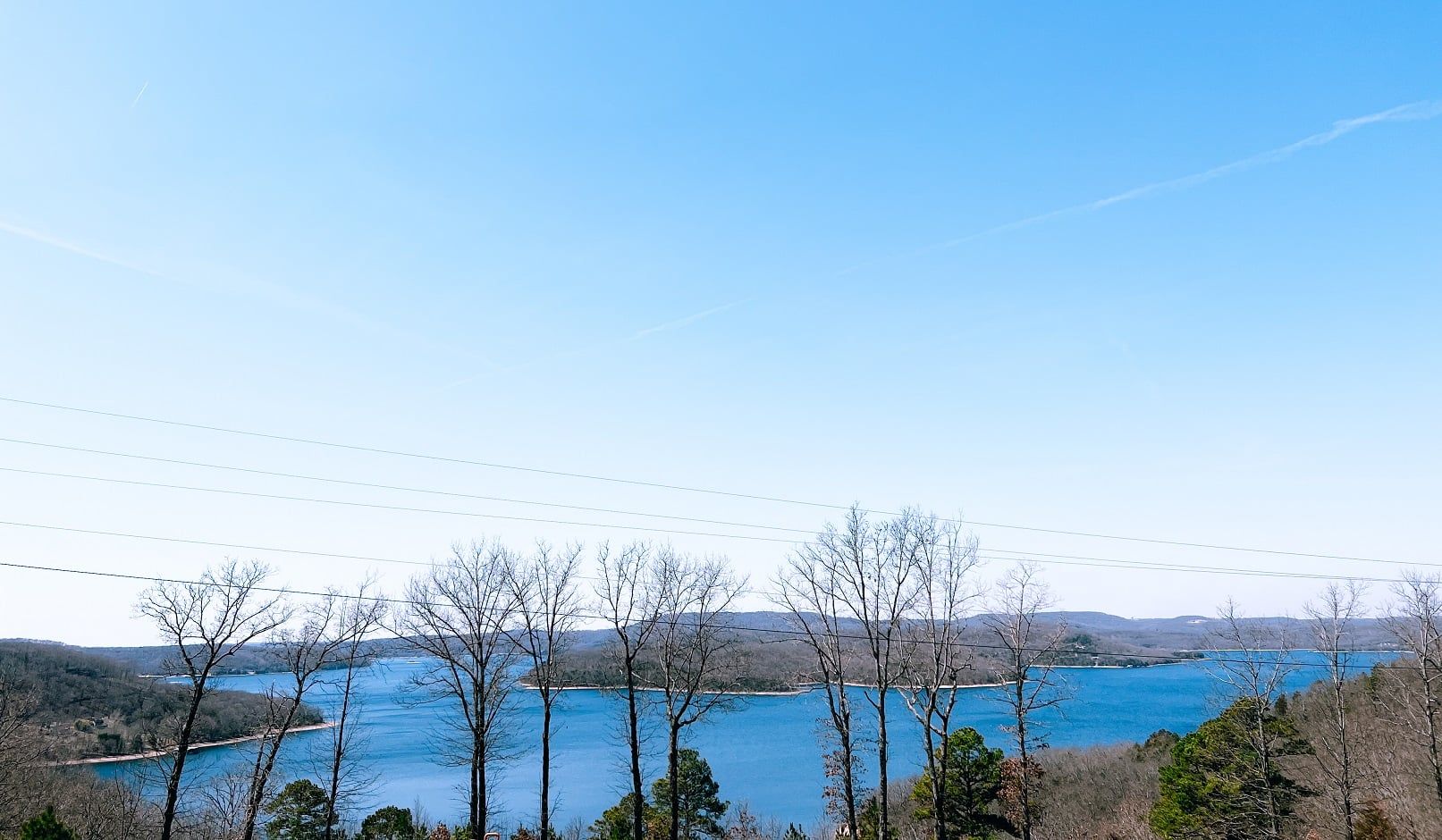 A view of a lake surrounded by trees on a sunny day.