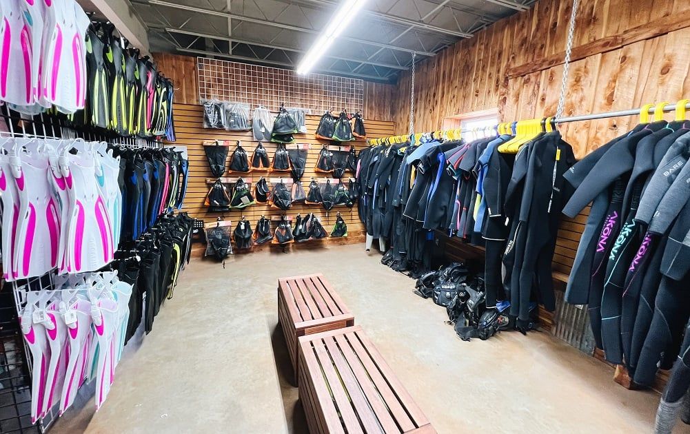 A store filled with lots of wet suits hanging on racks.