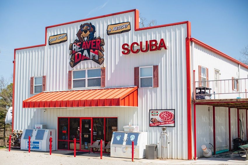 A white building for Dam Dive Shop with red trim and the word scuba on it.