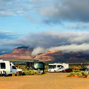 A group of rvs are parked in a field with mountains in the background.