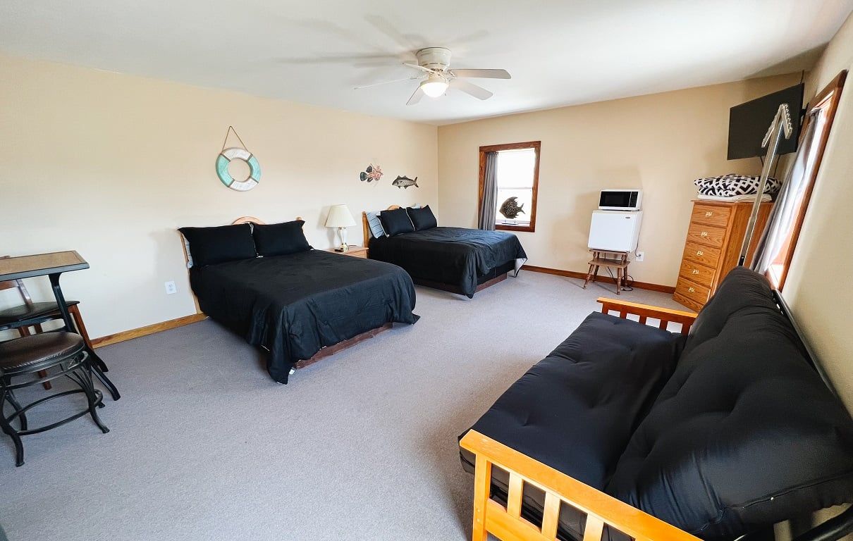 A motel room with two beds and a futon.