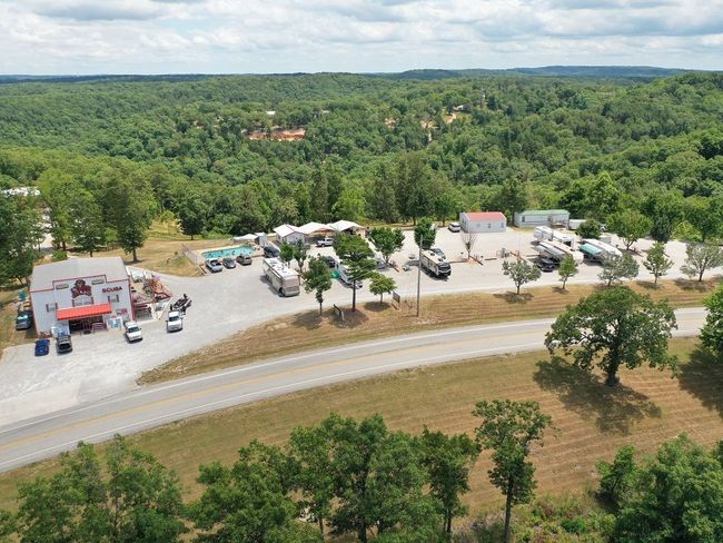 An aerial view of Dam Dive's parking lot surrounded by trees and a road.