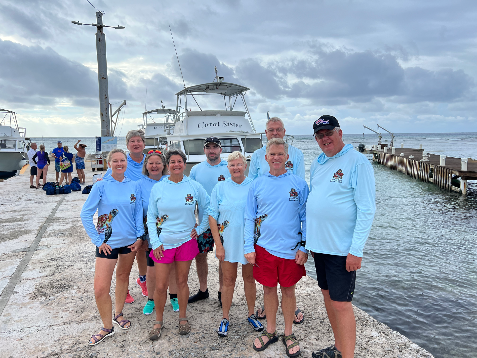 A group of people are posing for a picture in front of a boat in Cayman