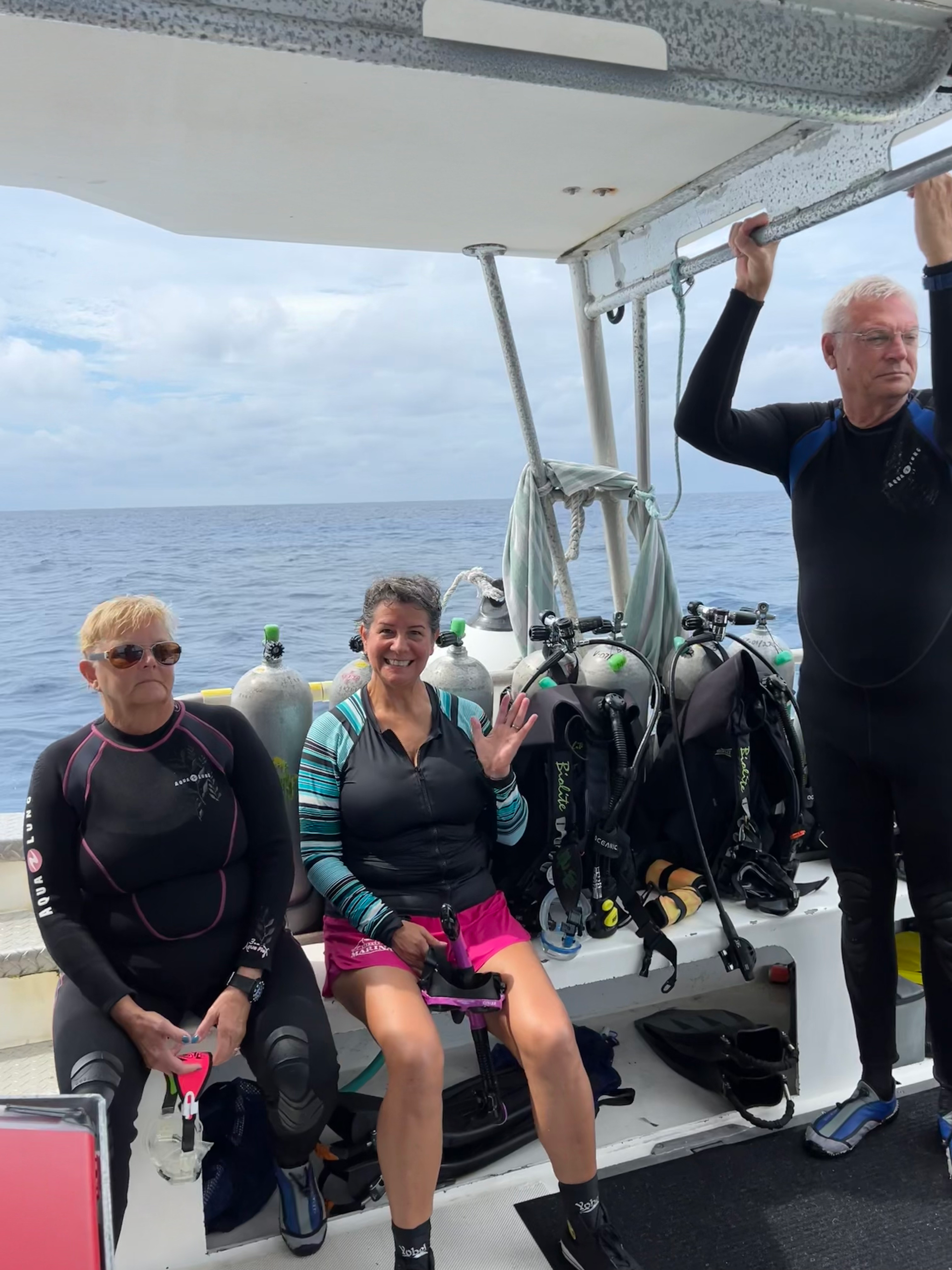 A man and two women are sitting on a boat in the ocean at Cayman.