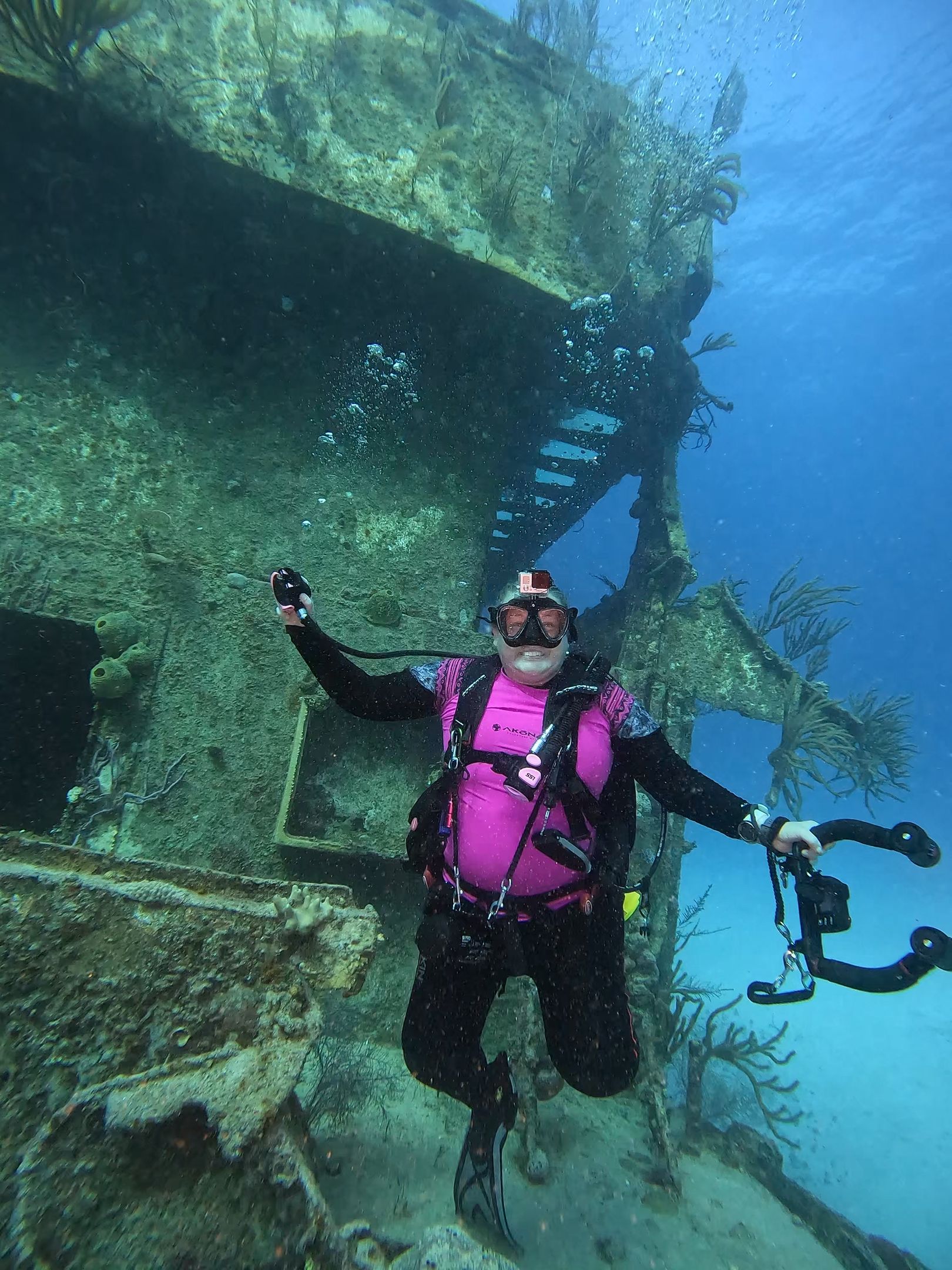 A man is scuba diving in the ocean near a shipwreck.