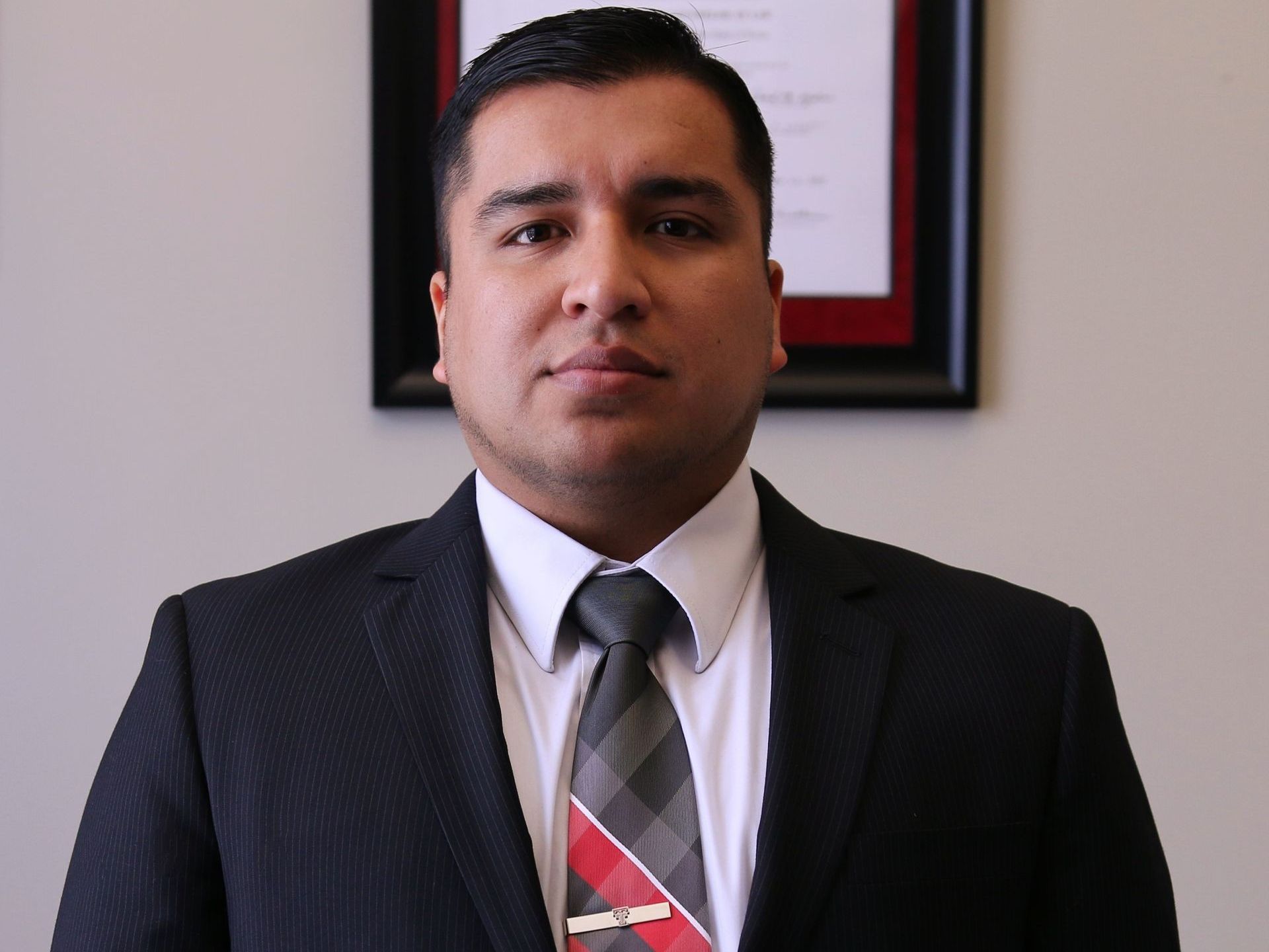 A man in a suit and tie stands in front of a framed picture