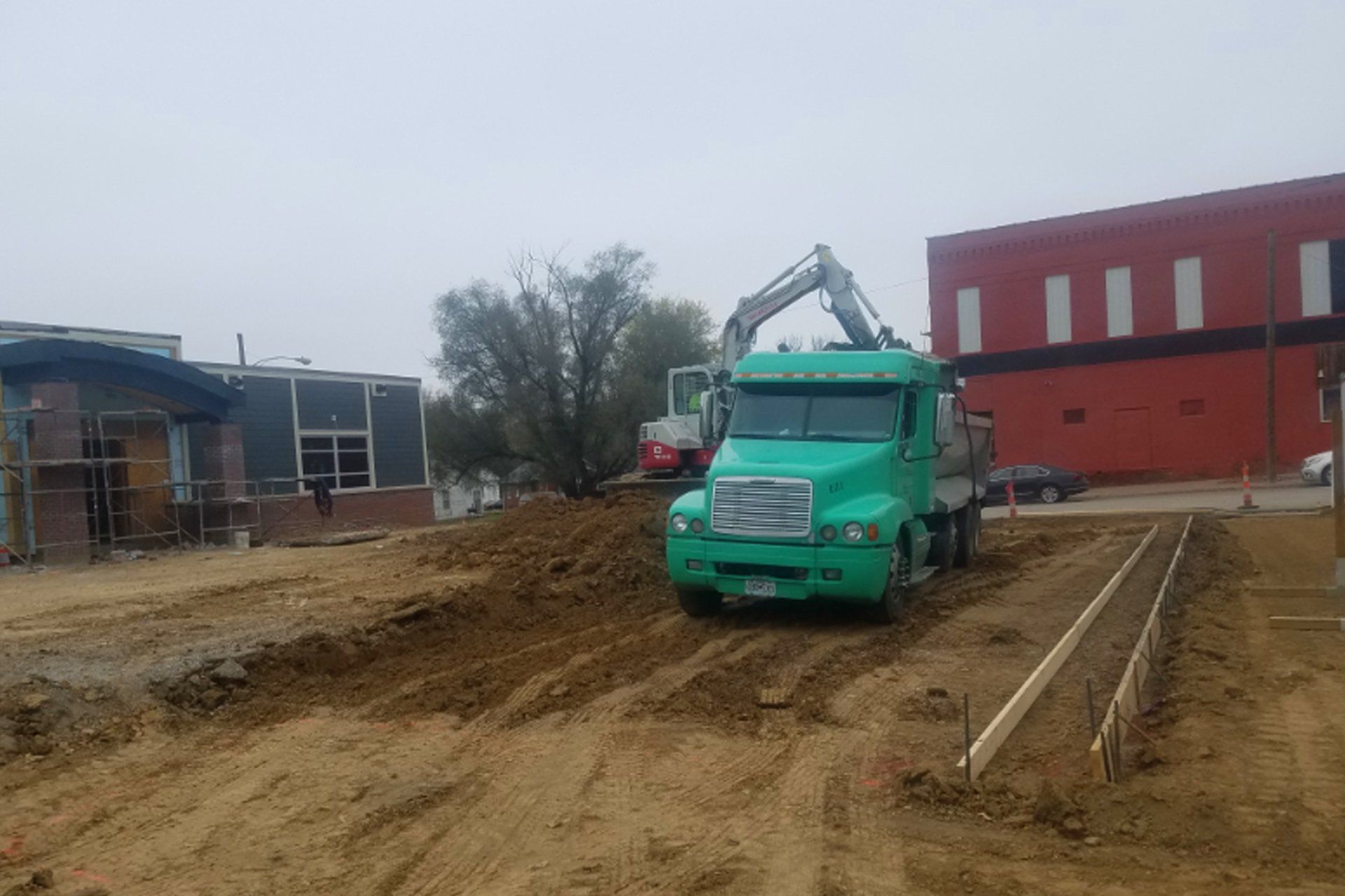Green truck and excavator on a construction site.