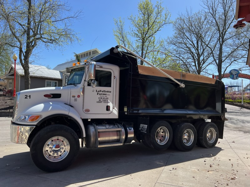 White and black dump truck parked on a paved surface on a sunny day.
