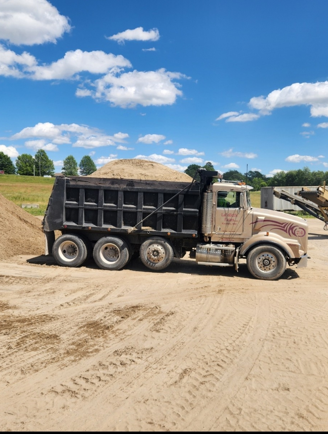 Dump truck filled with sand parked on a sand lot.