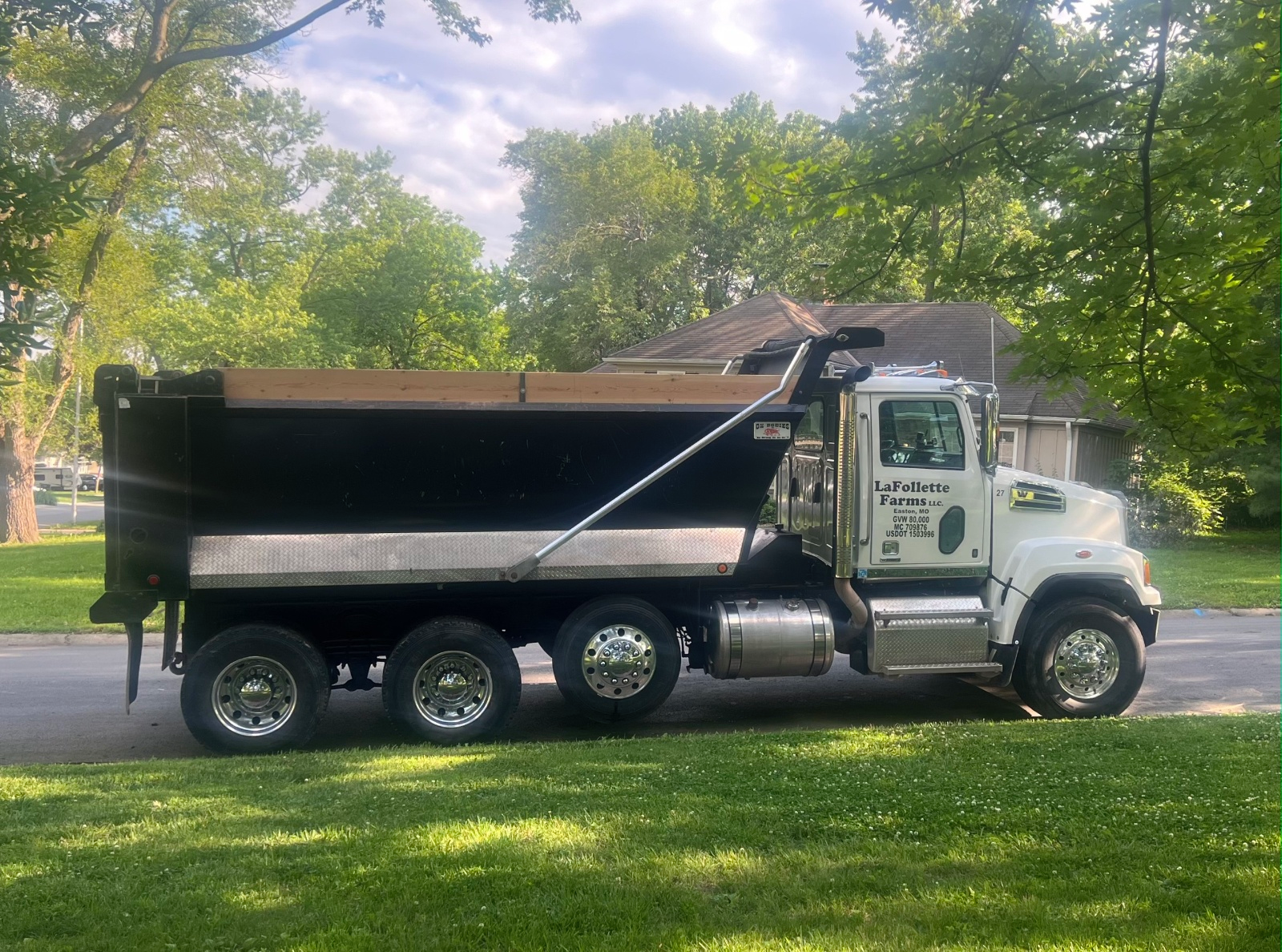 White dump truck on grass in front of a house.