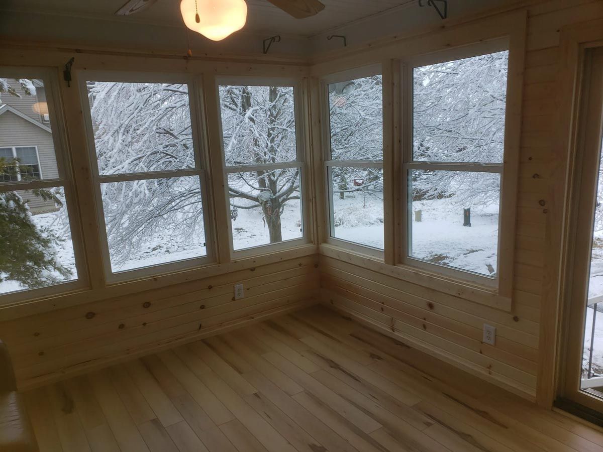A room with a lot of windows and a view of a snowy forest located in Mahomet, IL.
