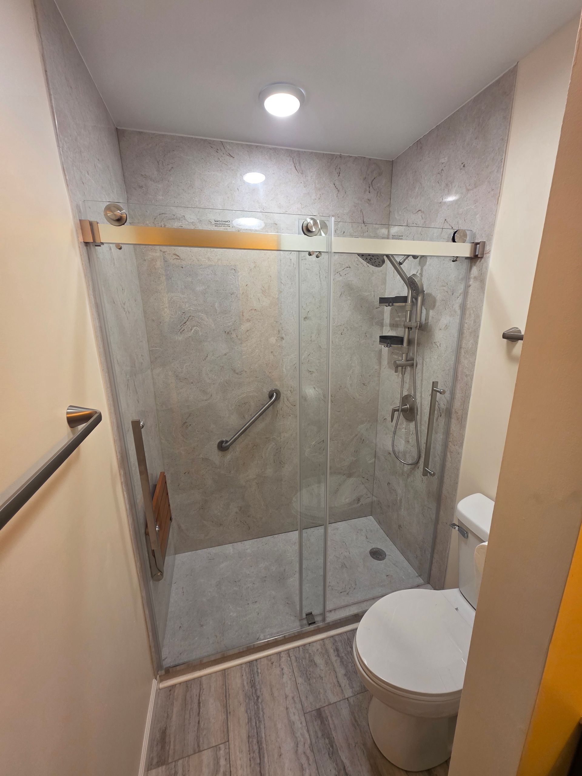 Small bathroom with tiled shower, sliding glass door, grab bar, and toilet. - Savoy, IL