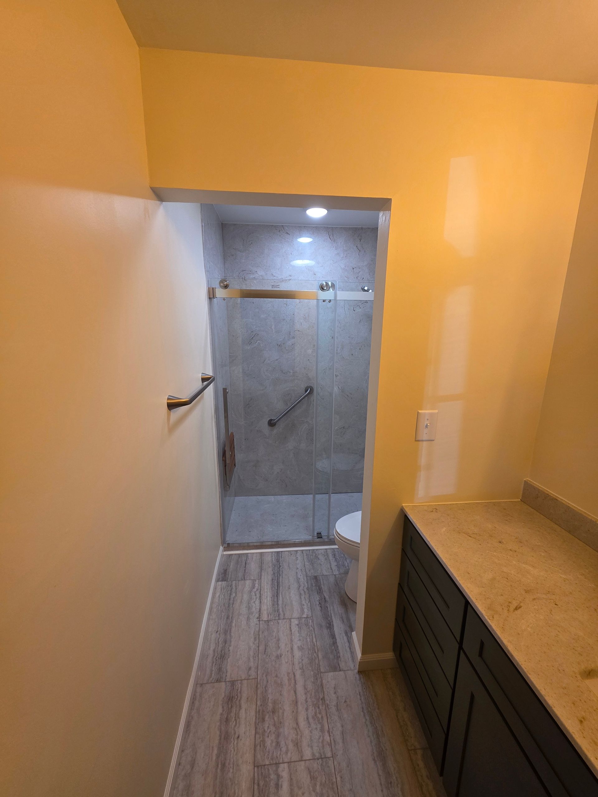 Bathroom with shower, vanity, and light-colored walls. Gray tiled floor leads to glass shower enclosure. - Savoy, IL