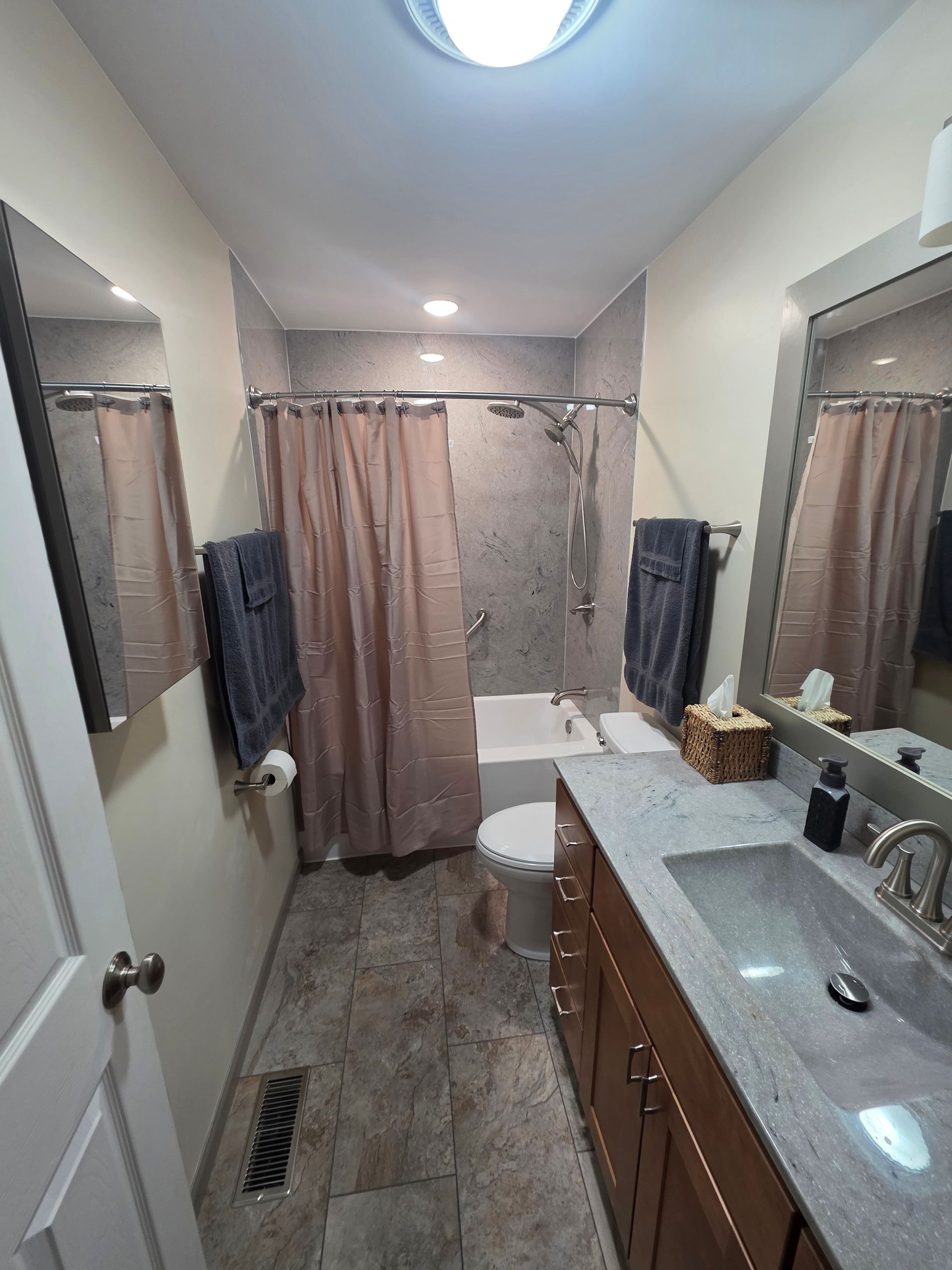 Bathroom with a vanity, toilet, bathtub/shower, and two mirrors.