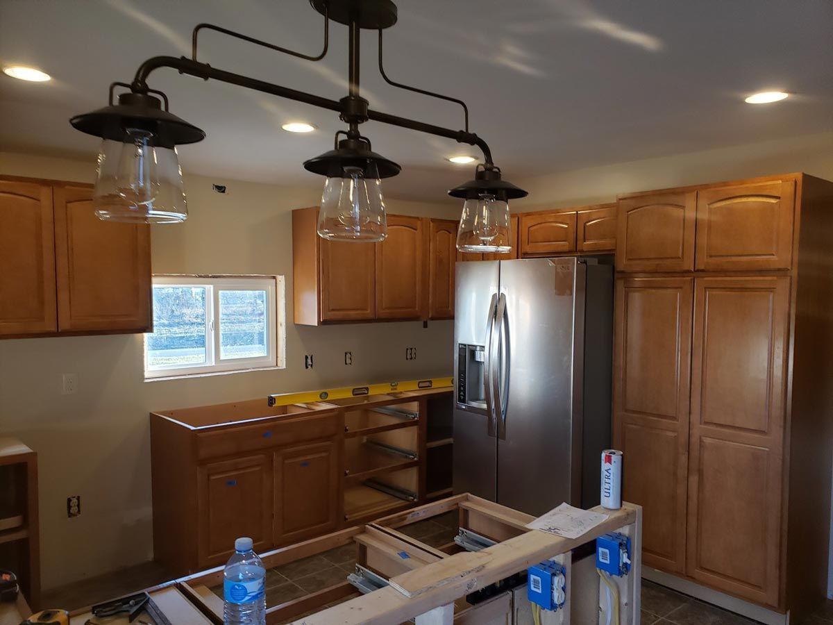 A kitchen under construction with wooden cabinets and a stainless steel refrigerator located in Urbana, IL,