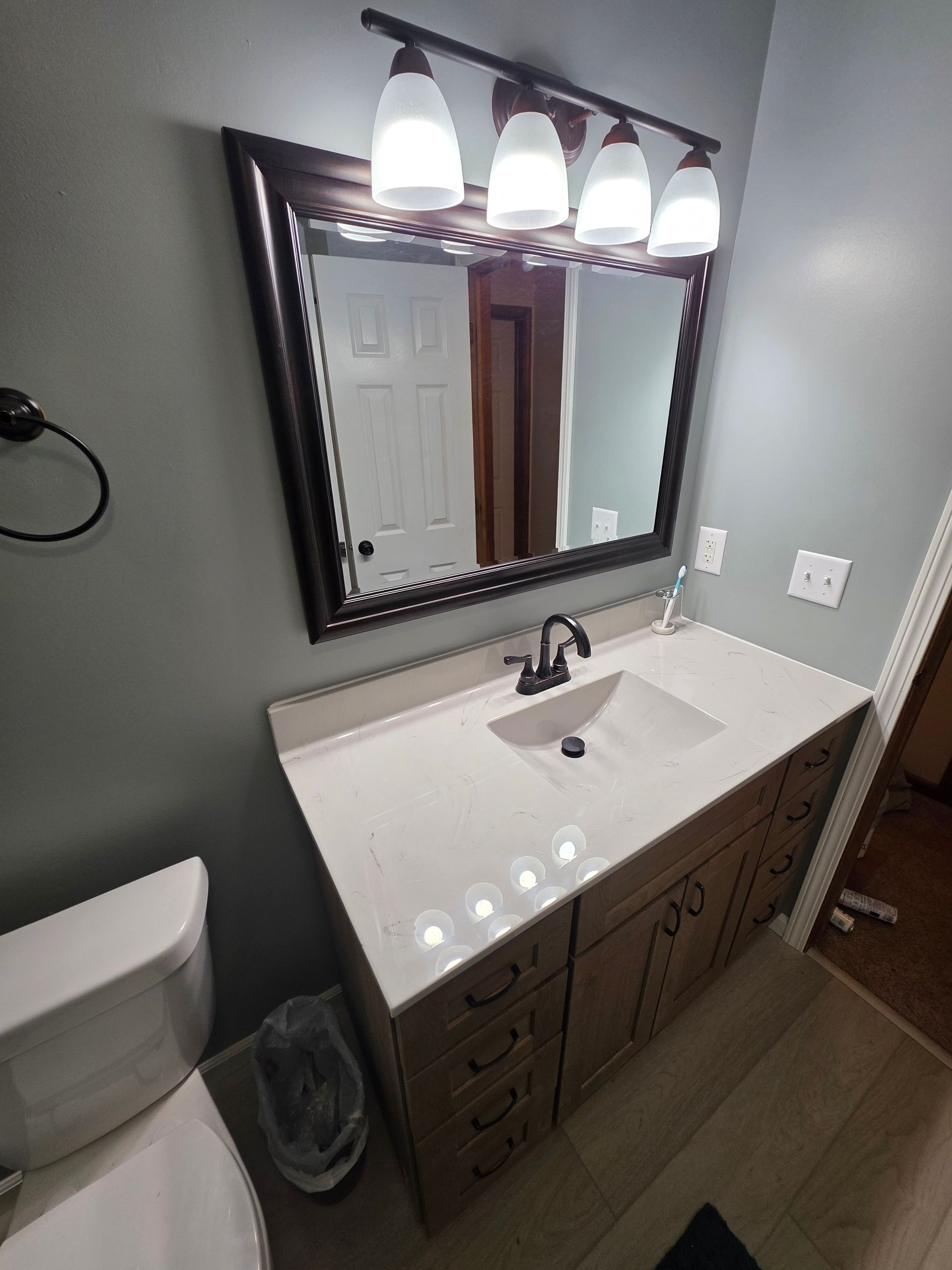 Bathroom vanity with mirror, light fixture, toilet, and sink. Beige cabinet, white countertop, gray walls. | Danville, IL