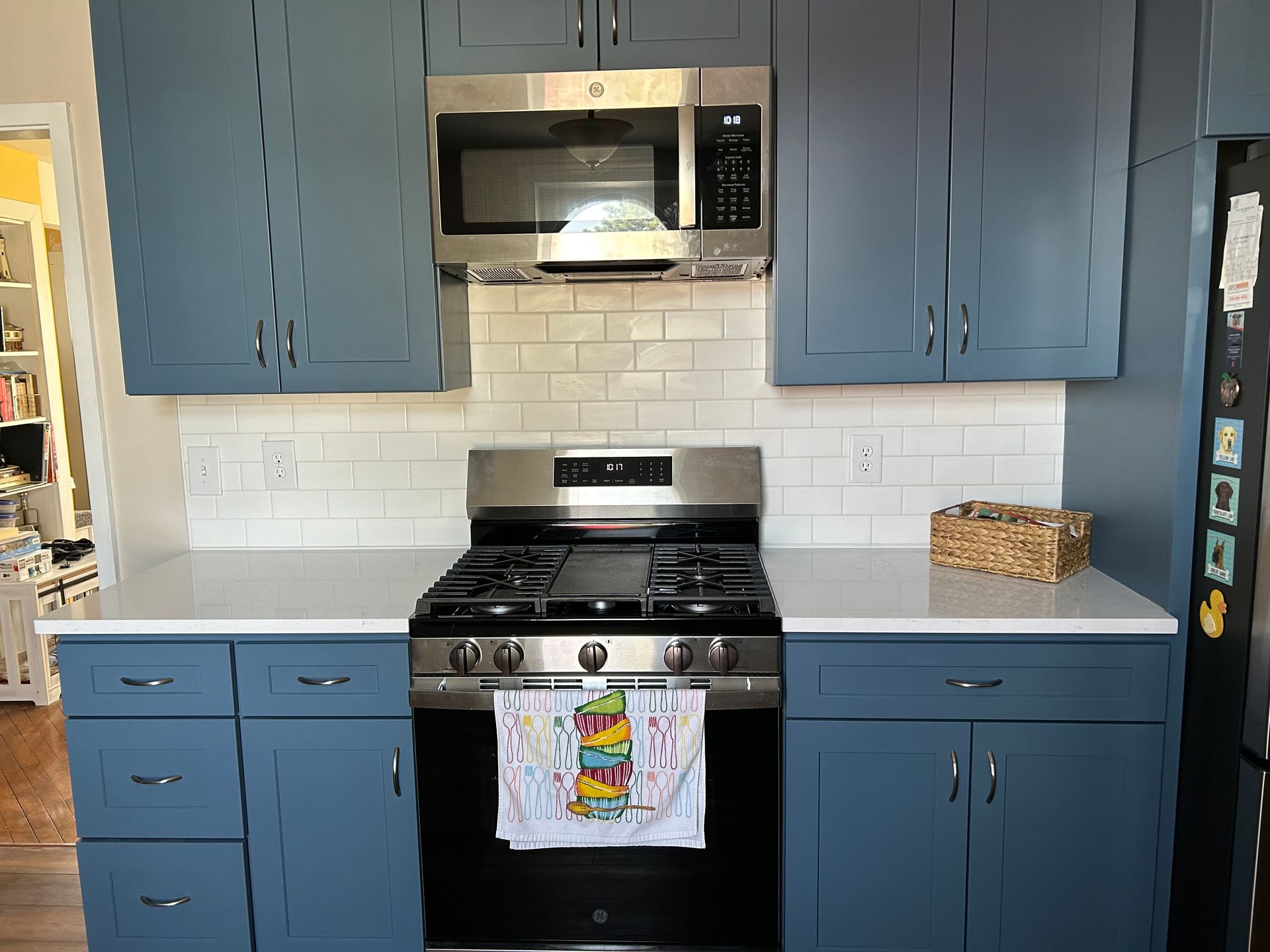 A kitchen featuring dark blue cabinets, white countertops, a white subway tile backsplash, and stainless steel appliances. St. Joseph IL