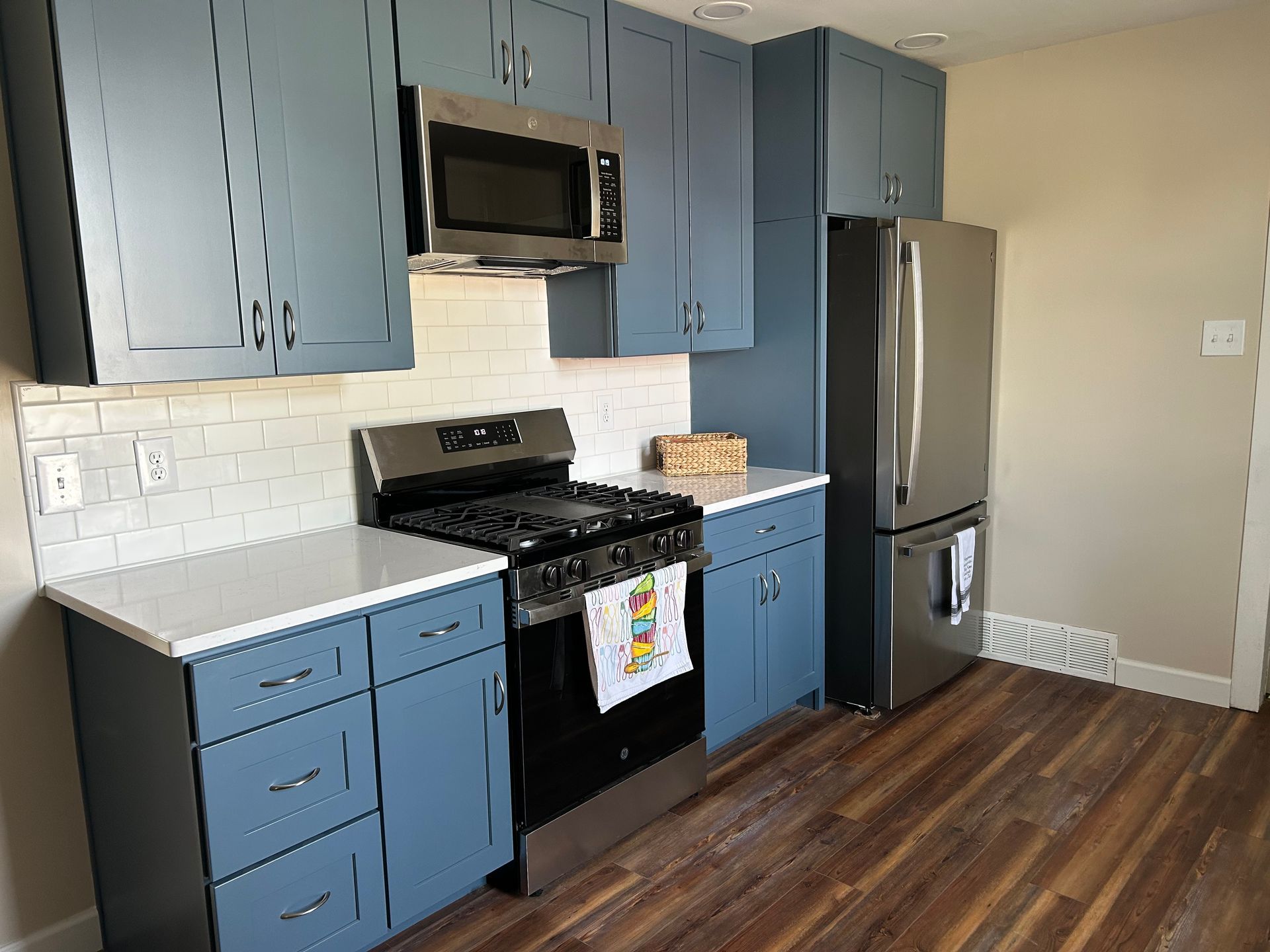 A kitchen with blue cabinets, white countertops, a subway tile backsplash, and stainless steel appliances. St. Joseph IL