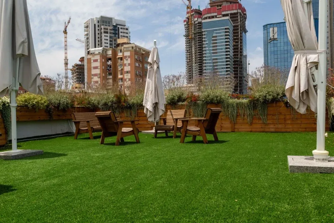 Rooftop patio with wooden furniture and synthetic turf.