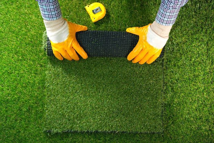 Professional measuring a section of turf for installation.