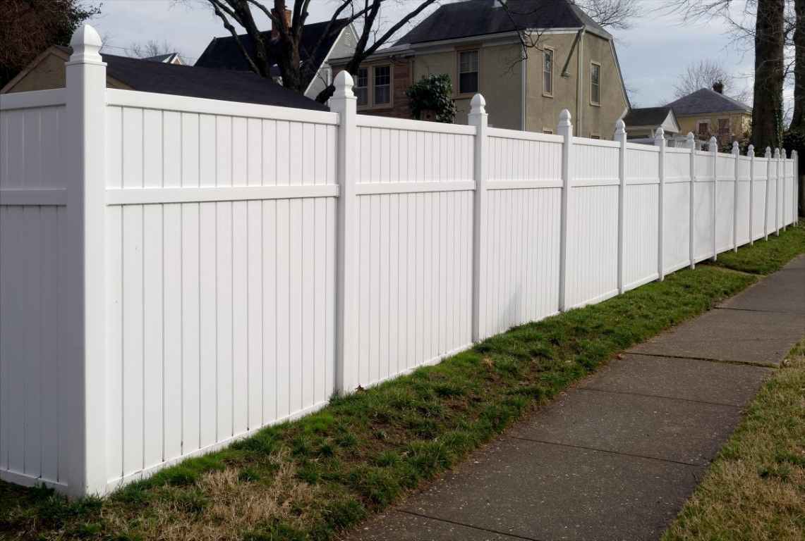 White vinyl privacy fence and matching gate in a backyard garden.