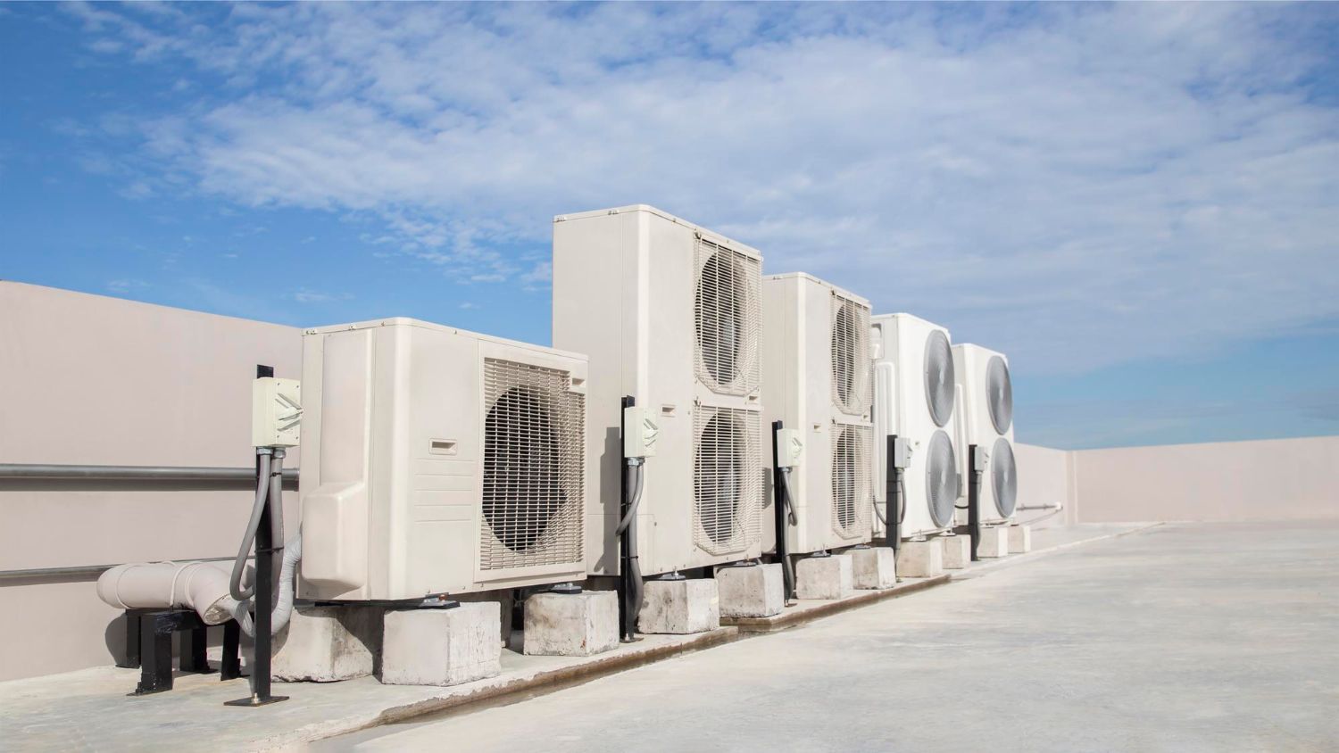A row of air conditioners are lined up on the side of a building.