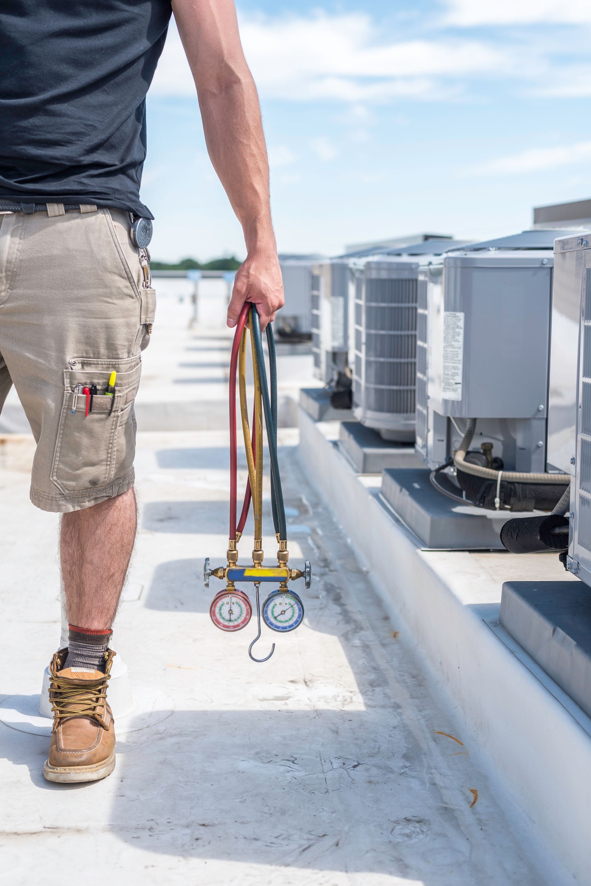 A man is standing on a roof holding a couple of gauges.